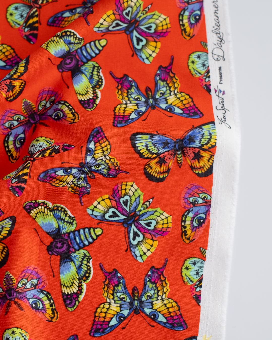 Cotton quilting fabric pattern called 'Butterfly Kisses in Papaya'. Part of the 'Daydreamer' fabric collection. Designed by Tula Pink for fabric company Free Spirit Fabrics. SKU: PWTP172.PAPAYA. 44-45 inch width.